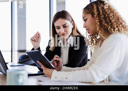 Businesswomen working together on tablet PC in coworking office Stock Photo