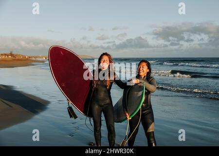 Surfers holding hands standing with surfboards at beach, Gran Canaria, Canary Islands Stock Photo
