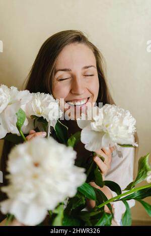 Happy woman with peony flowers at home Stock Photo