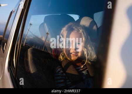 Smiling boy looking through window in car Stock Photo