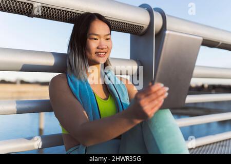 Smiling woman using tablet PC in front of railing Stock Photo