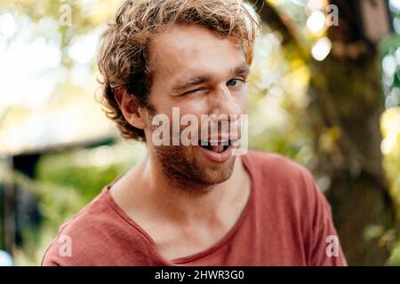 Young man winking eye outdoors Stock Photo