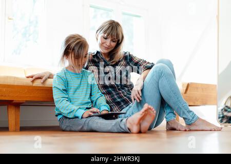 Mother looking at son using digital tablet on floor at home Stock Photo