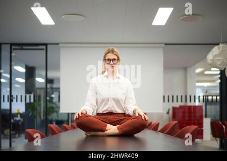 Confident businesswoman sitting on conference table in meeting room at modern office Stock Photo