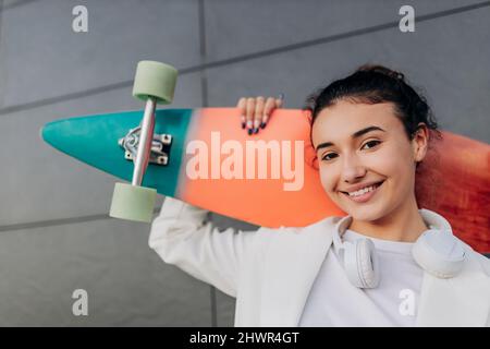 Smiling young woman with multi colored skateboard Stock Photo