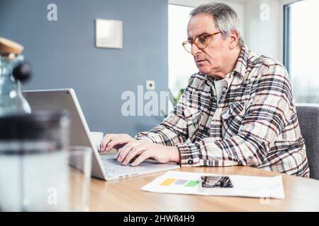 Man typing on laptop sitting at table Stock Photo
