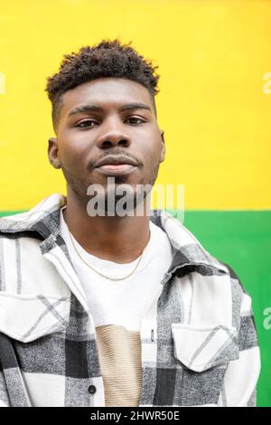 Smiling young man in front of yellow and green wall Stock Photo