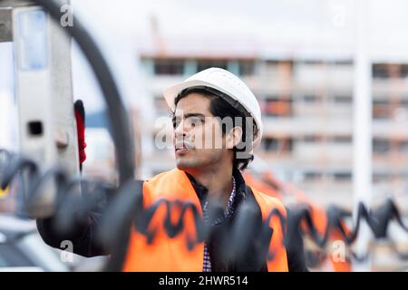 Engineer wearing hardhat examining machinery outdoors Stock Photo