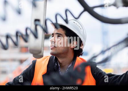 Engineer wearing hardhat examining machinery outdoors Stock Photo