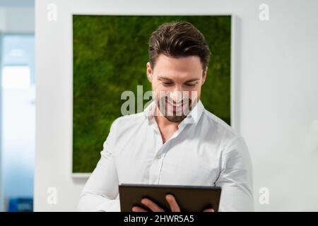 Smiling businessman working on tablet PC in office Stock Photo