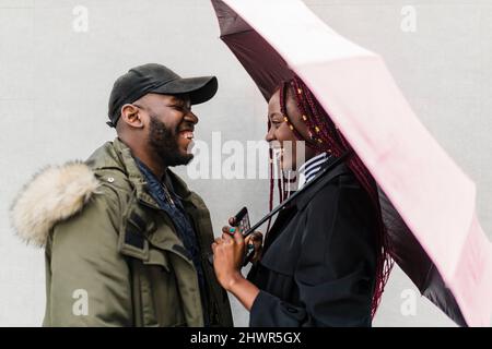 Happy young couple looking at each other by wall Stock Photo