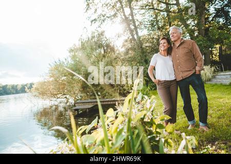 Man and woman with hands in pockets standing by lake Stock Photo
