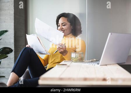 Smiling businesswoman analyzing documents in office Stock Photo