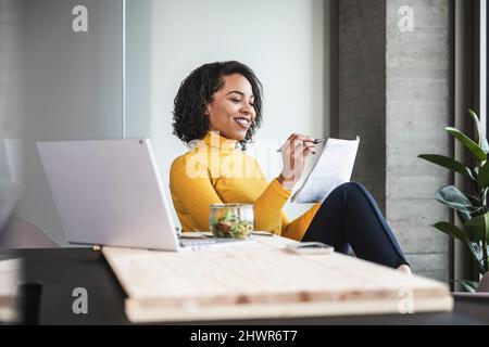 Young businesswoman examining paper documents at desk in office Stock Photo