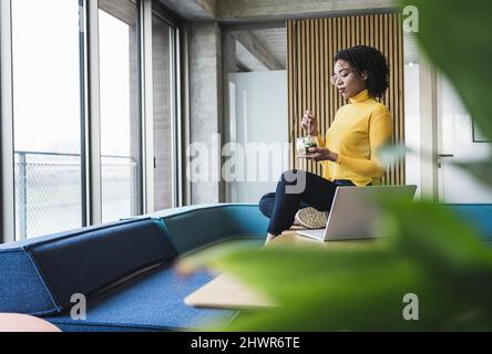 Businesswoman having salad by laptop at desk in office Stock Photo