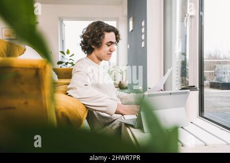 Smiling student with papers and tablet PC studying at home Stock Photo