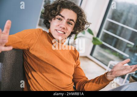 Young man with brown hair gesturing sitting at home Stock Photo