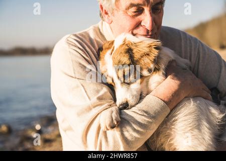 Senior man hugging dog on sunny day Stock Photo