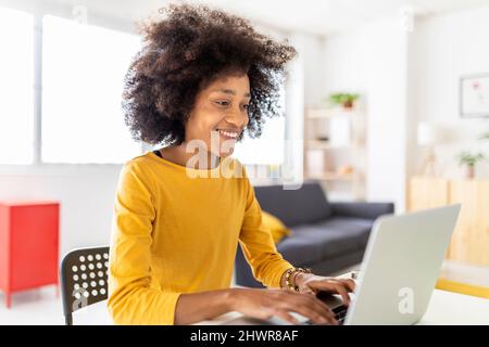 Happy young woman using laptop at home Stock Photo