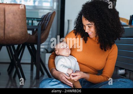 Smiling mother looking at baby boy sitting on ground Stock Photo