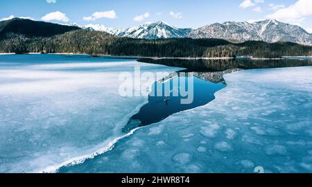 Germany, Bavaria, Aerial view of lone man paddleboarding between ice floes in Eibsee lake Stock Photo