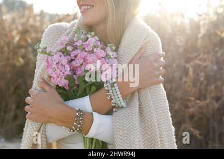 Cheerful woman holding pink flower bouquet on the beach Stock Photo