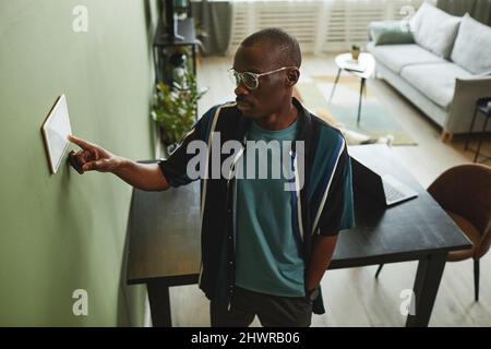 High angle portrait of black man using smart home control panel in modern interior Stock Photo