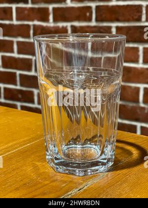 Close-up of an empty tall transparent glass on a wooden table. Stock Photo