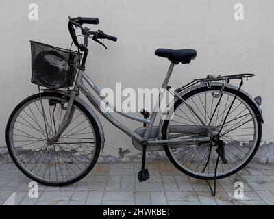 Rusty old vintage bicycle parked next to a off-white wall. Stock Photo