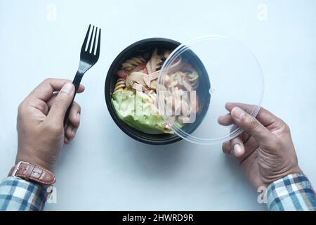 young man eating fresh vegetable salad in a plastic bowl  Stock Photo