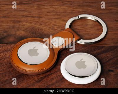 Bucharest, Romania - March 6, 2022: Apple Air Tags with brown leather keychain, on wooden background Stock Photo