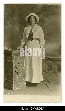 Original WW1 era postcard of serious attractive young woman, called Winifred, wearing an army service corps. sweethearts badge on her scarf, a long skirt and open necked blouse, a hat. Circa 1914, 1915. U.K. Stock Photo