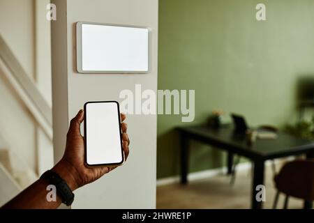 Minimal close up African American man holding phone with blank screen while connecting to smart home system, copy space Stock Photo