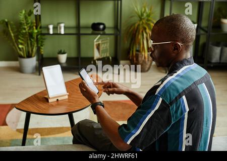 Portrait of African American man connecting phone to smart home system in modern interior Stock Photo