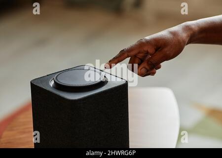 Minimal close up of male hand pushing button on smart speaker with home AI, copy space Stock Photo