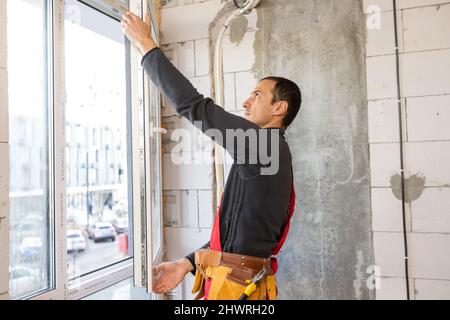 Construction worker repairing windows in house. Stock Photo