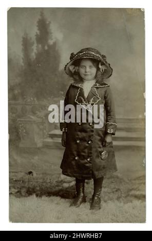 Original WW1 era postcard of a smartly dressed pretty young girl in a large hat and wearing a matching coat, wearing gloves and holding a purse. Photographed by Elizabeth Maria ‘Lizzie’ East, Park Lane Studio,  Caemawr Road, Morriston, Swansea, Wales, dated May 14 1914 Stock Photo