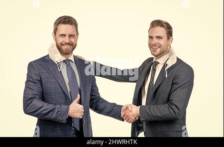 colleagues in respirator mask shaking hands after successful deal during pandemic, business meeting. Stock Photo