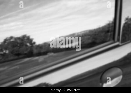 Blurred photo of rural landscape reflected in side window of a car. Black white abstract photo. Stock Photo