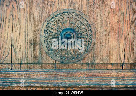 Weathered wooden door with decorative round handle. Aged photo. Stock Photo