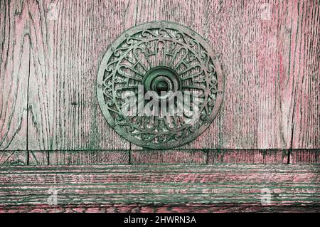 Weathered wooden door with decorative round handle. Toned image. Stock Photo