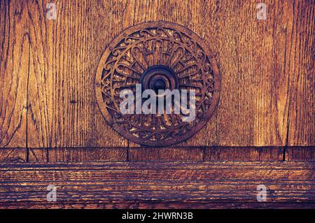 Weathered wooden door with decorative round handle. Toned dark image.