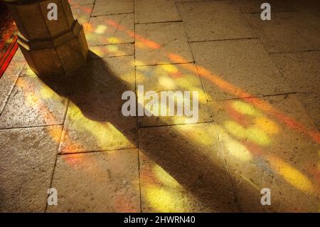 Colorful light spots on the the floor in church. Sunlight filtered through the stained glass window. A game of light and shadow. Stock Photo