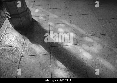 Light spots on the the floor in church. Sunlight filtered through the stained glass window. A game of light and shadow. Aged photo. Black and white. Stock Photo