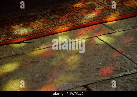 Colorful light spots on the the floor and carpet in church. Sunlight filtered through the stained glass window. A game of light and shadow. Stock Photo
