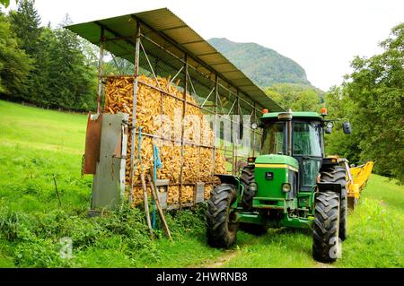 Haute-Savoie, France - August 23, 2015: John Deere 3350 tractor next to corn dryer barn for animal feeding at small farm. Stock Photo