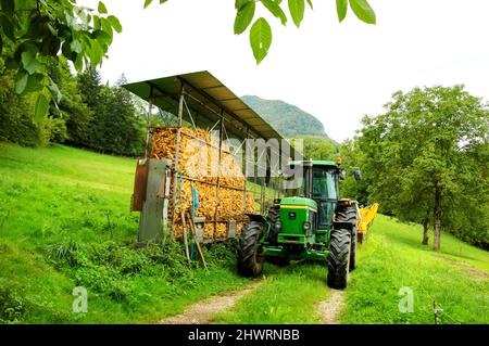 Haute-Savoie, France - August 23, 2015: John Deere 3350 tractor next to corn dryer barn for animal feeding at small farm. Stock Photo