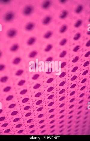 Vertical perforated surface highlighted by pink neon led lights. Abstract backgrounds and textures Stock Photo