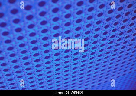 Abstract perforated wall background highlighted by blue neon led lights. Patterns and textures Stock Photo