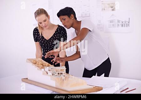 We have to get this right before construction starts. Shot of two female architects discussing an architectural model. Stock Photo